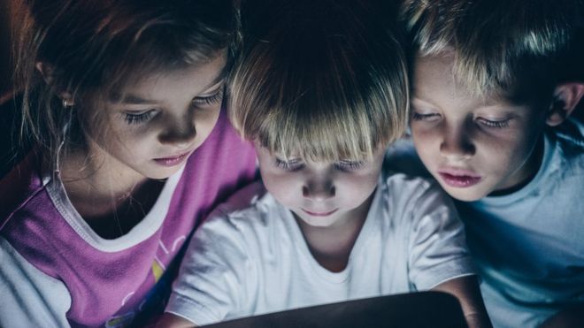 Children looking at a tablet at night
