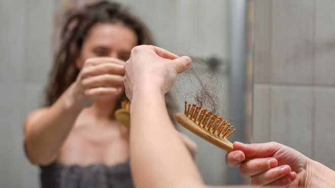 Mujer con un cepillo lleno de pelo