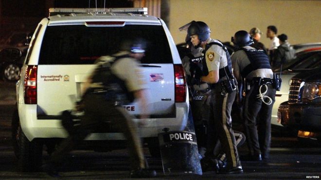 Полицейский бежит, чтобы укрыться после того, как стреляли в полицейского, причастного к стрельбе в Фергюсоне, штат Миссури, 9 августа 2015 года.