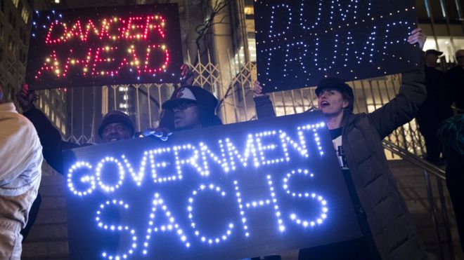 Активисты выступают против заявленных президентом Дональдом Трампом планов ослабить правила Уолл-стрит и отменить закон Додда-Франка, когда они идут к штаб-квартире Goldman Sachs в Нижнем Манхэттене, 7 февраля 2017 года в Нью-Йорке.