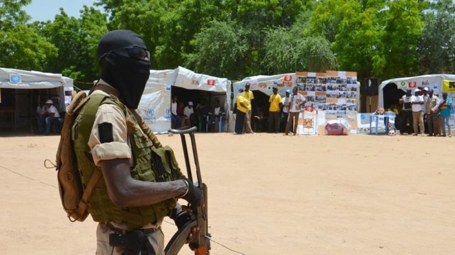 A Niger soldier stands guard near information stands in a camp for internally displaced people in Diffa, Niger, in 2016