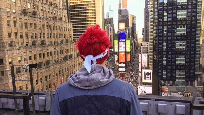 Ниндзя смотрит на небоскреб Нью-Йорка. Его две торговые марки наиболее заметны - флуоресцентные, окрашенные волосы и бандана.