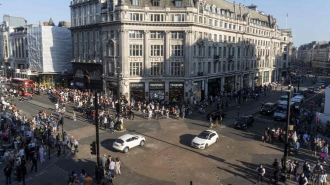 Пешеходы и транспортные средства пересекают перекресток после того, как полиция очистила активистов по борьбе с изменением климата, блокирующих дорогу в Оксфордском цирке