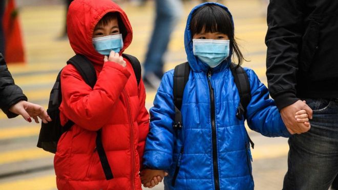 Two children wearing face masks and holding hands