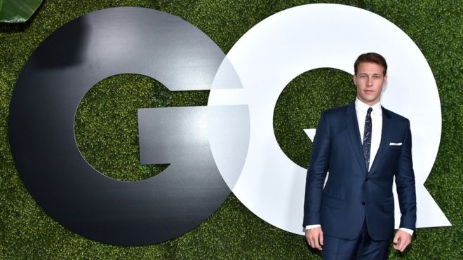 Человек перед логотипом GQ