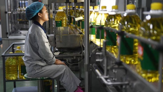 На этом снимке, сделанном 19 июля 2018 года, изображен рабочий, следящий за производственной линией соевого масла на заводе Hopeful Grain and Oil Group в Саньхэ, в северной китайской провинции Хэбэй.