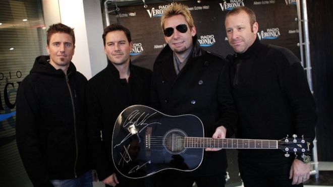 Members of Canadian rock band Nickelback pose with a signed guitar in Naarden