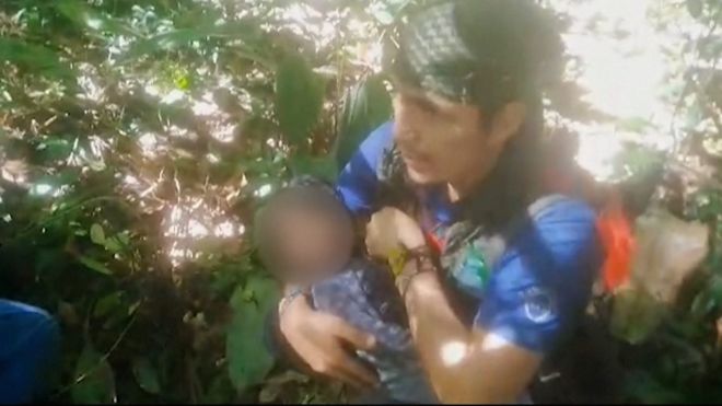 Man holding young child in his arms in the middle of the jungle