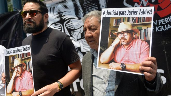 Two men holding up pictures of Javier Valdez