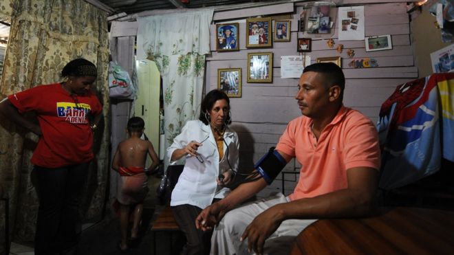 Кубинский врач Нильда Мария Лейсека помогает мужчине в его доме в районе Ла-Вега, Каракас