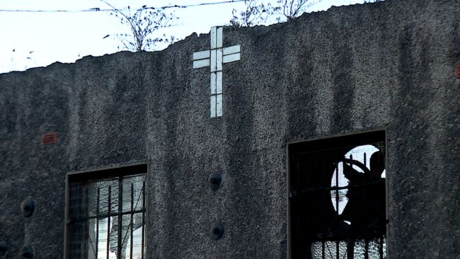 Задняя часть заброшенного здания, крест, выложенный плиткой на стене