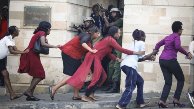 Женщины эвакуируются со сцены, поскольку сотрудники службы безопасности разыскивают нападавших во время продолжающегося обстрела и взрывов в Найроби, Кения, 15 января 2019 года.
