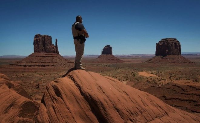 Рейнджер парка навахо смотрит на Долину монументов, управляемую навахо
