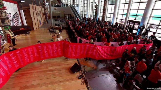 Волонтеры разворачивают свиток с именами 2800 жертв канадских школ-интернатов.