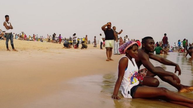 Couple sit down close to di water for beach