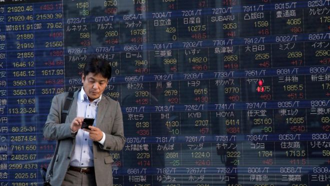 Man stands in front of stock boards in Japan