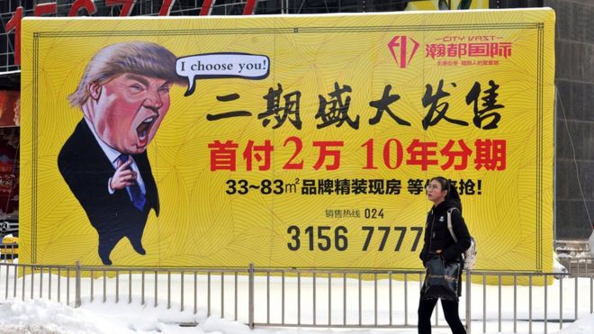 Пешеход проходит мимо рекламы недвижимости с изображением мультфильма президента Дональда Трампа в Шеньяне в провинции Ляонин на северо-востоке Китая. 22 февраля 2017 г.
