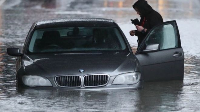 Мужчина с автомобилем на затопленной улице Шеффилда после проливного дождя в этом районе.