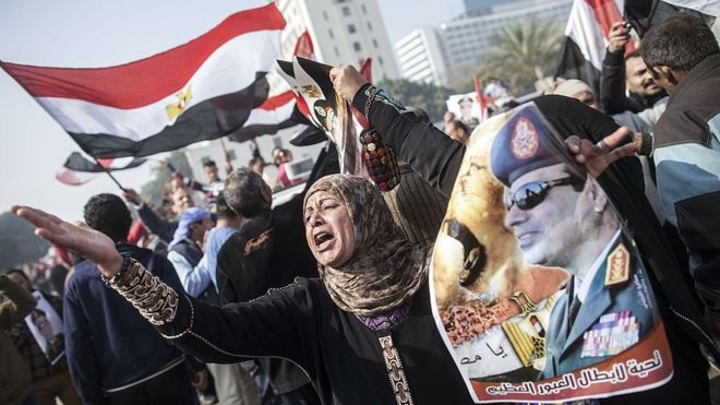 Сторонник египетского правительства держит плакат Абдул Фаттах ас-Сиси на митинге в Каире, посвященном третьей годовщине революции 25 января 2014 года