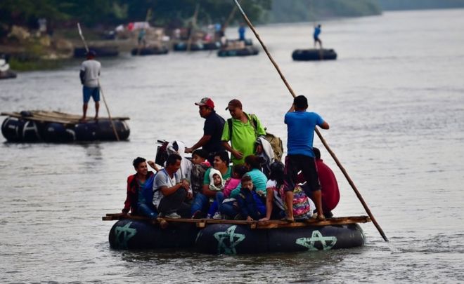 Несколько самодельных плотов перевозят мигрантов через реку