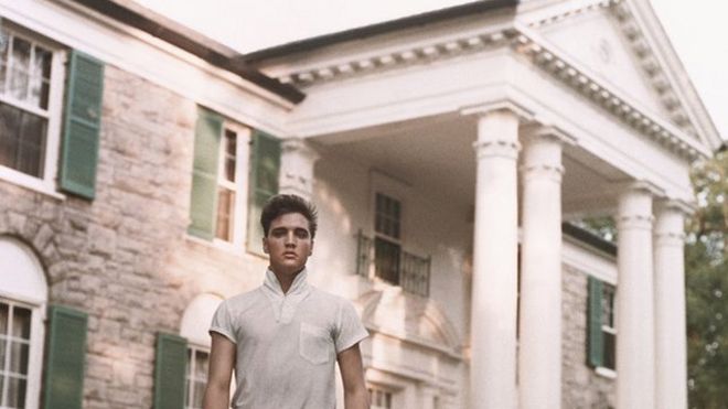 Elvis Presley, joven, delgado y vestido de blanco, frente a su casa, que le costó 100.000 dólares en 1957.