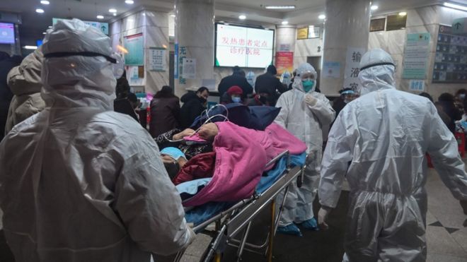 Медицинский персонал переносит пациента в больницу Красного Креста Ухани
