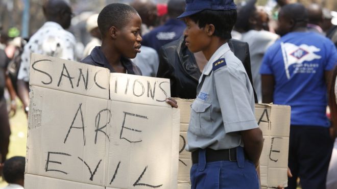 Protester in Zimbabwe holds placard calling sanctions evil