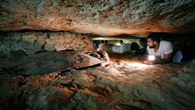 Arqueólogo observa tumba em Menia, no Egito
