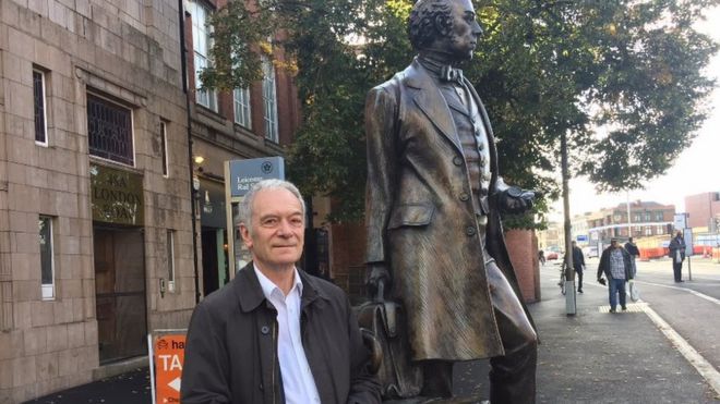 Айвор Джеймс стоит рядом со статуей Томаса Кука