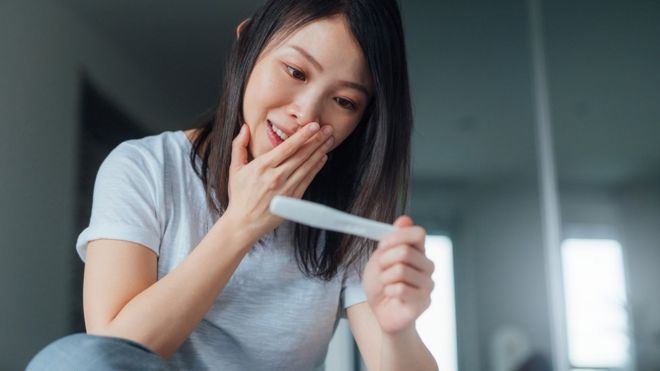 Una mujer mira los resultados de su prueba de embarazo.
