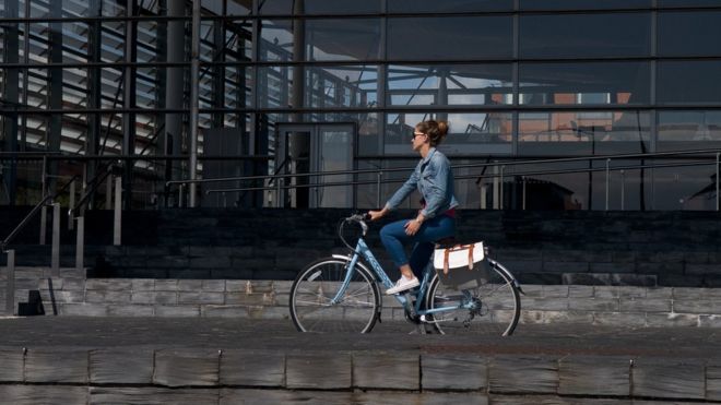Женщина едет на велосипеде мимо Сенедда