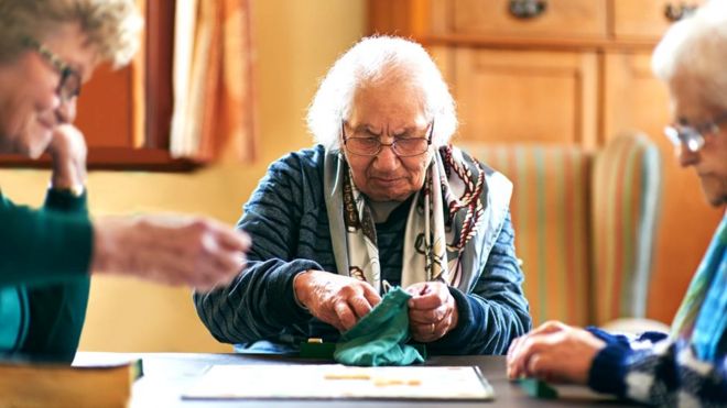 Пожилые люди в доме престарелых играют в настольную игру