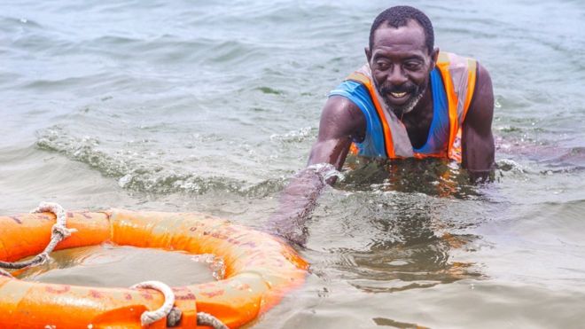 Спасатель Николас Пол плавает со спасательным кругом в Лагосе, Нигерия