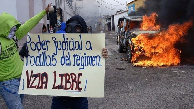 Студент показывает плакат с надписью «Судебная власть стоит на коленях перед режимом. Свободная Венесуэла »во время акции протеста против правительства президента Венесуэлы Николаса Мадуро в Сан-Кристобале, Венесуэла, 3 марта 2016 года.