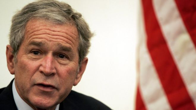 Expresidente George W. Bush con una bandera de Estados Unidos.
