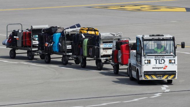 Грузовик тянет багажники на взлетно-посадочной полосе аэропорта