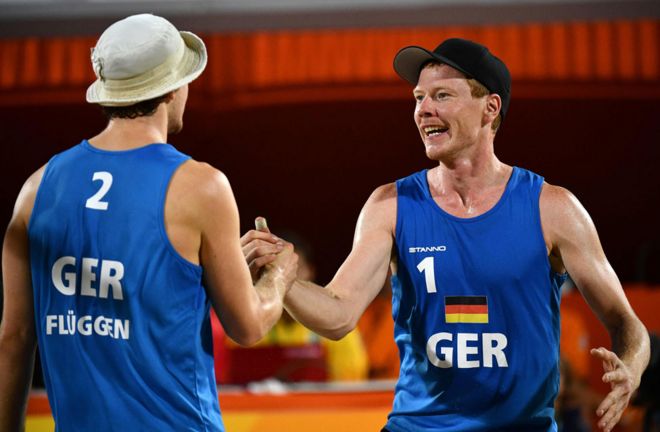 Ларс Флугген и Маркус Бокерманн из Германии отмечают победу во время отборочного матча по пляжному волейболу среди мужчин между сборными Нидерландов и Германии на арене пляжного волейбола в Рио-де-Жанейро 8 августа 2016 года