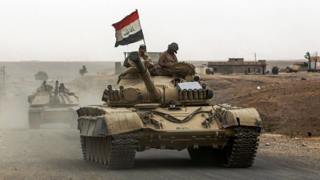 Iraqi soldiers ride atop a tank as they move towards the town of Shirqat, west of Hawija, on 20 September 2017