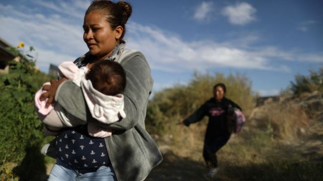 Una mujer inmigrante cruza el Valle del Río Grande con su bebé en brazos