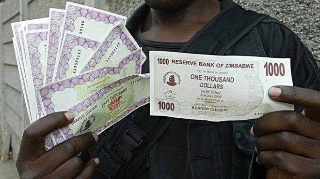 Житель Хараре держит банкноты в 1 000 и 50 000 долларов из-за инфляции в 2006 году