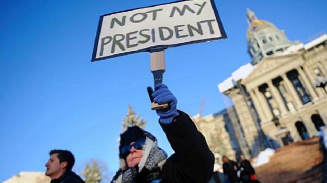 Suzanne Gould, 59, holds a sign during a demonstration against US President-elect Donald Trump outside the Colorado Capitol building on the eve of the Electoral College vote, in Denver, Colorado on December 18, 2016