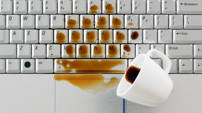 Una taza de café derramada sobre un teclado