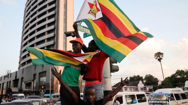 People holding Zimbabwean flags celebrate in the street after the resignation of Robert Mugabe as president on 21 November 2017 in Harare, Zimbabwe