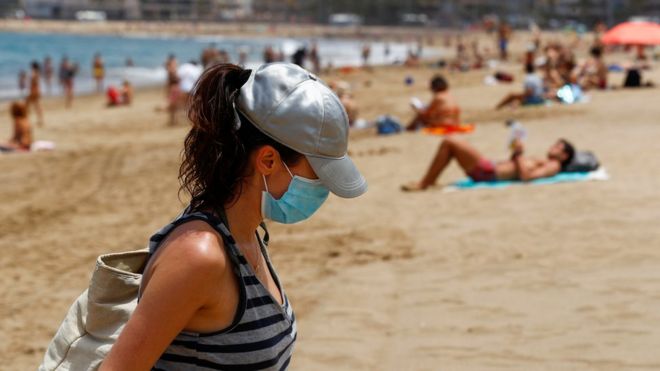Женщина в маске покидает пляж Лас-Кантерас, поскольку некоторым испанским провинциям разрешено ослабить ограничения на изоляцию во время второй фазы на фоне вспышки коронавирусной болезни (COVID-19) на острове Гран-Канария, Испания