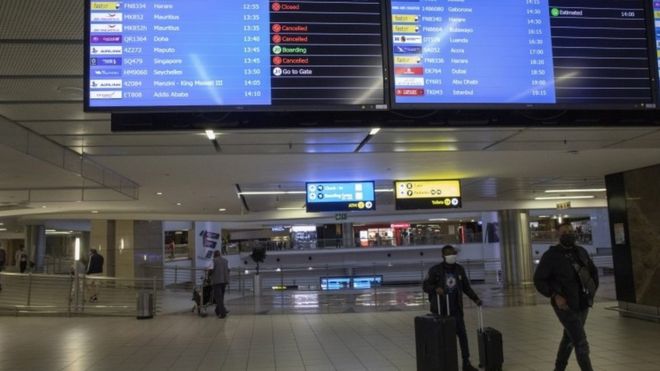 Des passagers marchent devant un panneau d'information sur les vols à l'aéroport de Johannesburg, en Afrique du Sud. Photo : 27 novembre 2021