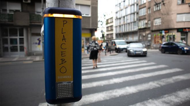 Taster na semaforu na prometnoj beogradskoj ulici, na njemu je crnim markerom napisano - PLACEBO