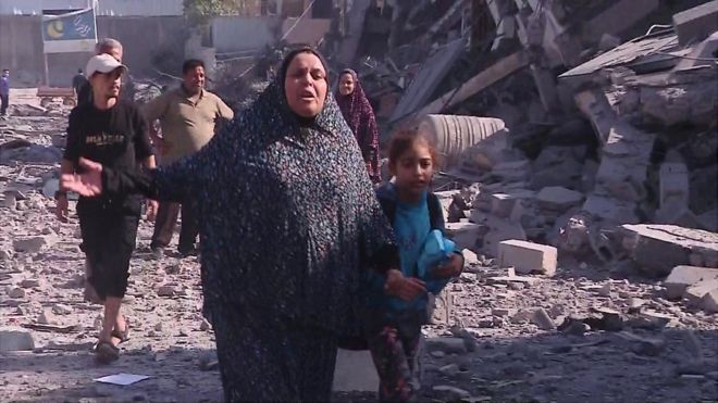 A woman and child in a destroyed neighbourhood in Gaza