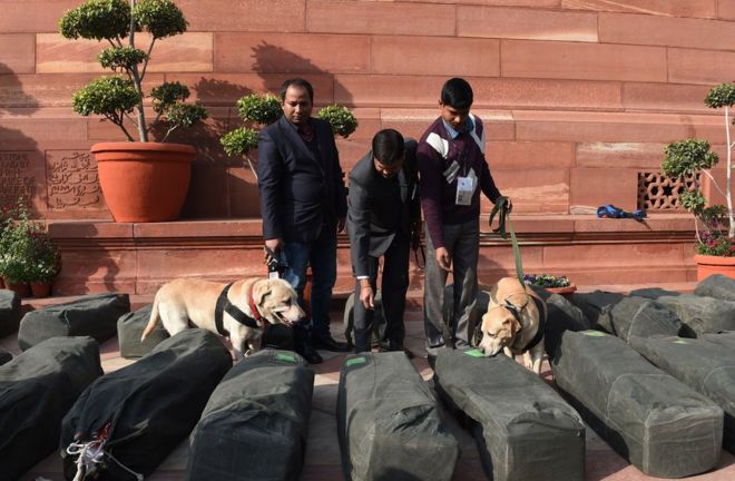 Индийские сотрудники службы безопасности проверяют пакеты с бюджетными документами возле здания парламента в столице Дели