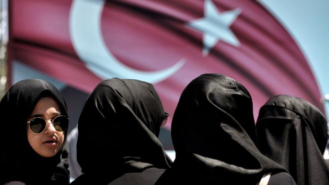 Женщина смотрит на демонстрацию в поддержку президента Турции Эрдогана (не изображена) в парке Сарачане в Стамбуле 19 июля 2016 года.
