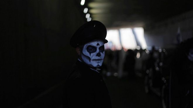 Мужчина в костюме скелета мертвого шофера сопровождает парад через подземный переход